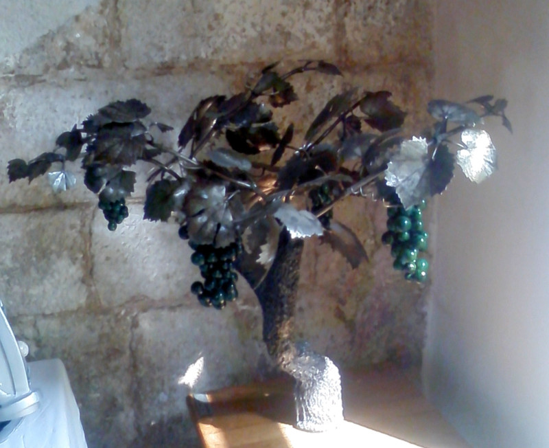 représentation d'une vigne avec un tronc réalisé à partir de soudure, des feuilles de vigne forgées et des grappes der raisin en raku.